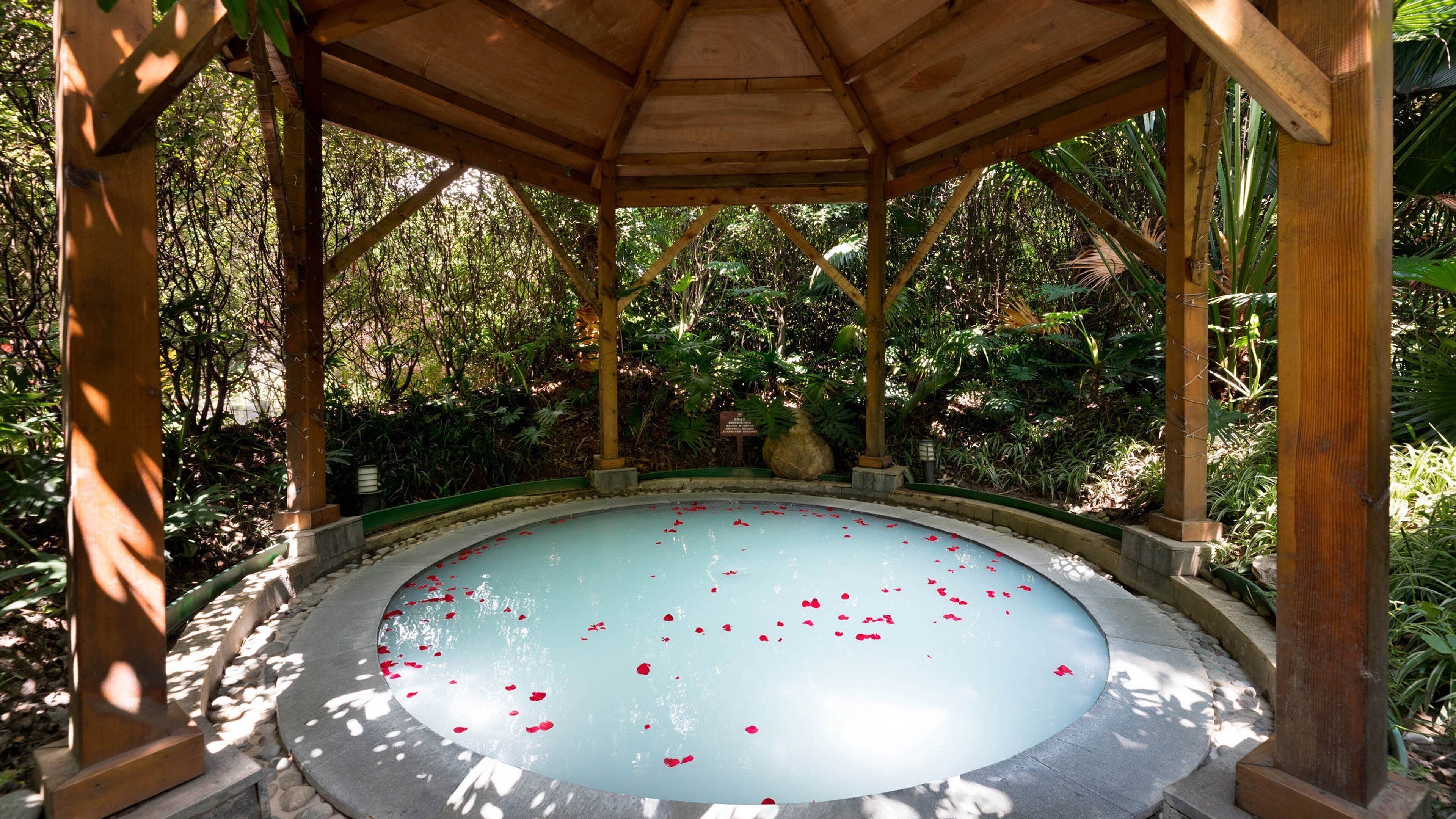 A gazebo with a circular pool surrounded by greenery.