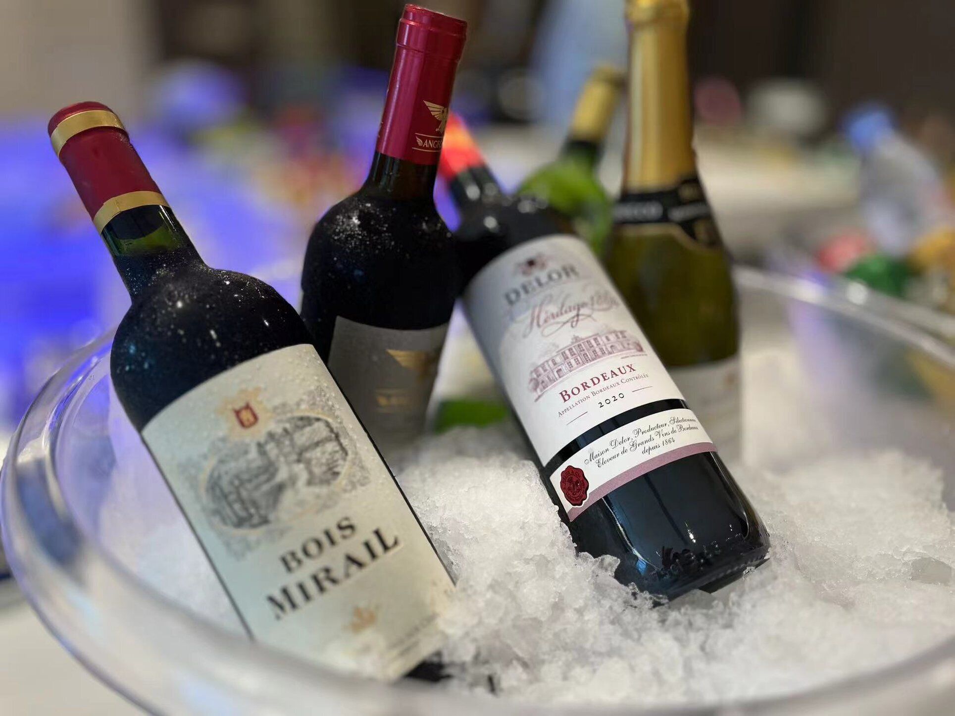 A selection of wine bottles in a glass bowl filled with ice.