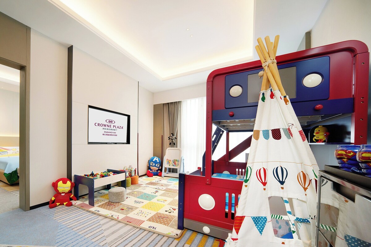 A children's play area with a red play structure, a white tent, and a variety of toys.