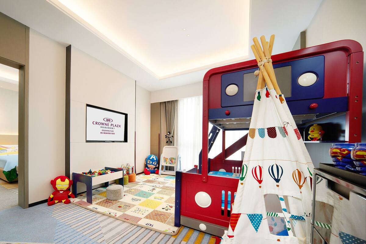 Zona de juegos infantiles con una estructura roja, una carpa blanca y diversos juguetes.