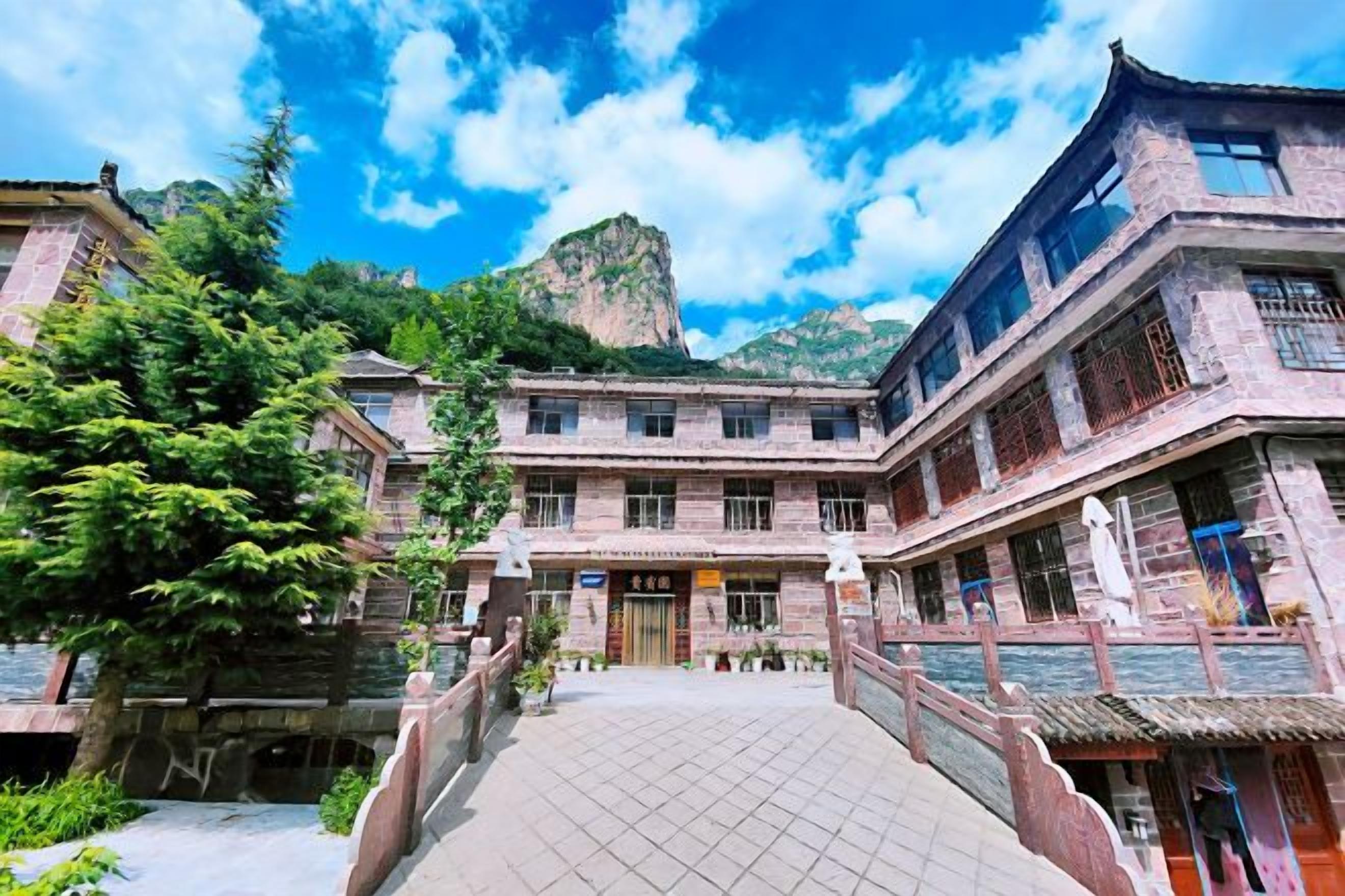 A traditional building with a courtyard, a bridge, and a mountain in the background.