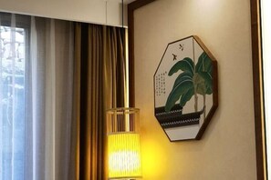 Una stanza con un'ampia finestra, una lampada e un quadro appeso al muro.