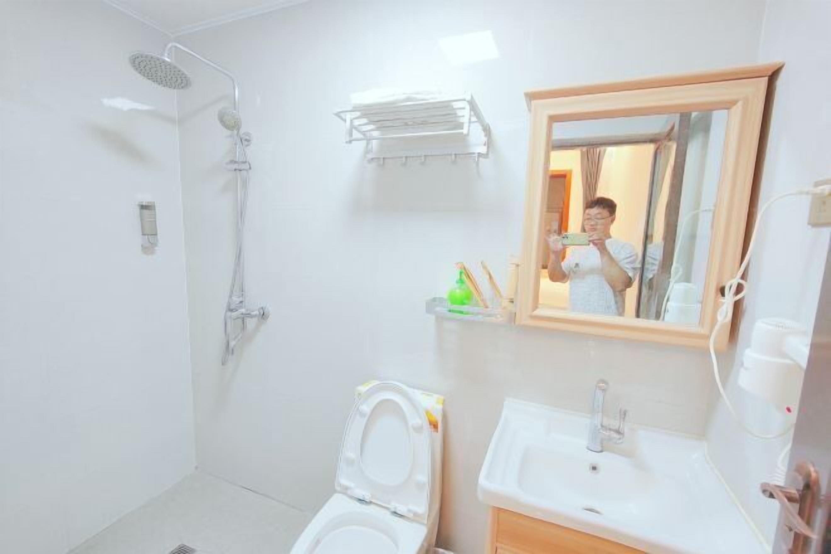 A bathroom with a shower, toilet, sink, and mirror.