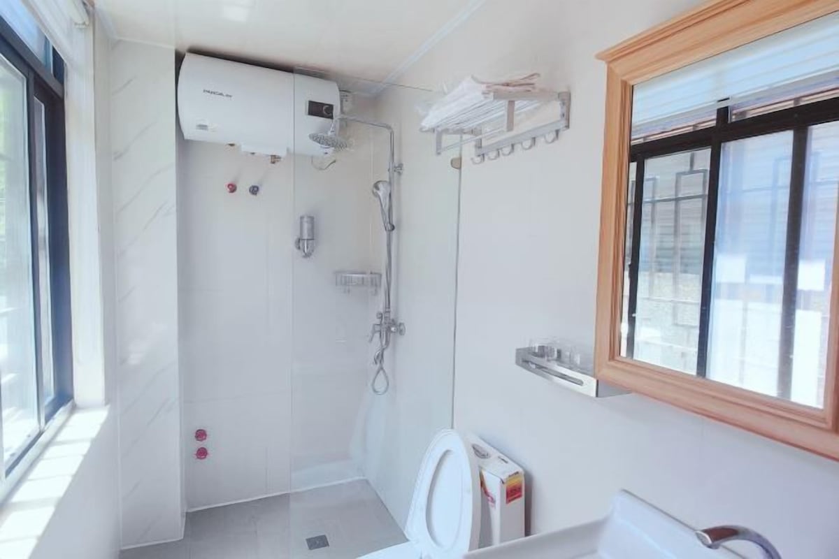 Un bagno moderno con il water, una doccia e una finestra.