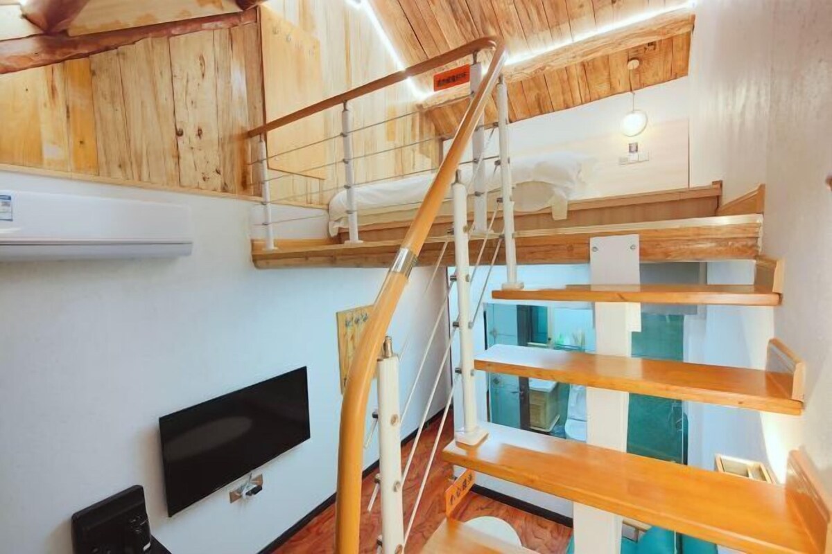 Un interno in legno a più livelli, con una scala, una TV a schermo piatto e un lampadario.