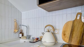 A kitchen with a white countertop, a kettle, a wooden cutting board, and a bottle of dish soap. - One minute from Place Masséna,  fully equipped STUDIO with balcony (Nice)