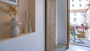 A hallway with a wooden door, a framed picture on the wall, and a view of the outside balcony. - One minute from Place Masséna,  fully equipped STUDIO with balcony (Nice)