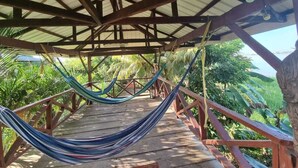 Un hamac suspendu sous une structure en bois, offrant une vue sur une végétation luxuriante.
