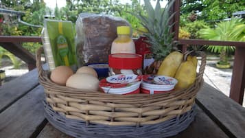 Una cesta de mimbre llena de alimentos sobre una mesa de madera.