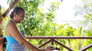 Une séance de massage en plein air, sur une terrasse en bois, avec vue sur un plan d’eau et la verdure environnante.