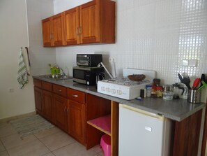 Una cocina con armarios de madera, microondas, estufa y diversos utensilios.