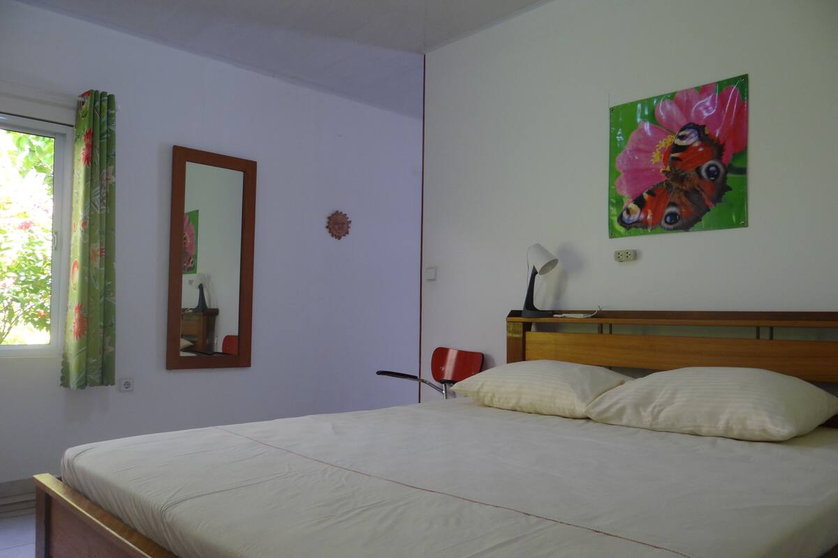 Un dormitorio con cama, espejo, escritorio y silla.