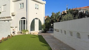 Un bâtiment moderne de couleur blanche, doté d’une pelouse bien entretenue et d’un chemin en pierre.