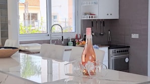 Une cuisine moderne dotée d’un îlot central, d’un coin repas et offrant une vue sur l’extérieur.