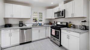 A modern kitchen with white cabinets, stainless steel appliances, and a granite countertop.