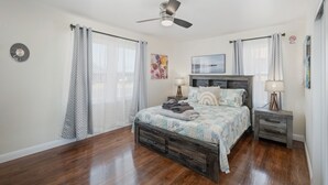 A bedroom with a bed, nightstands, a ceiling fan, and a clock on the wall.