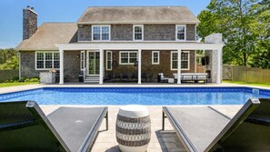 A two-story house with a swimming pool, outdoor seating, and a covered patio area.
