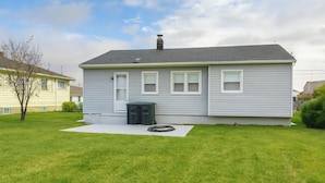 Een gelijkvloers huis met een grijze gevel, een voortuin en een klein voortuintje.
