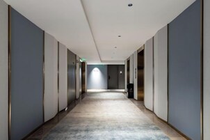 Un pasillo largo y estrecho con piso alfombrado que conduce a una puerta al final.