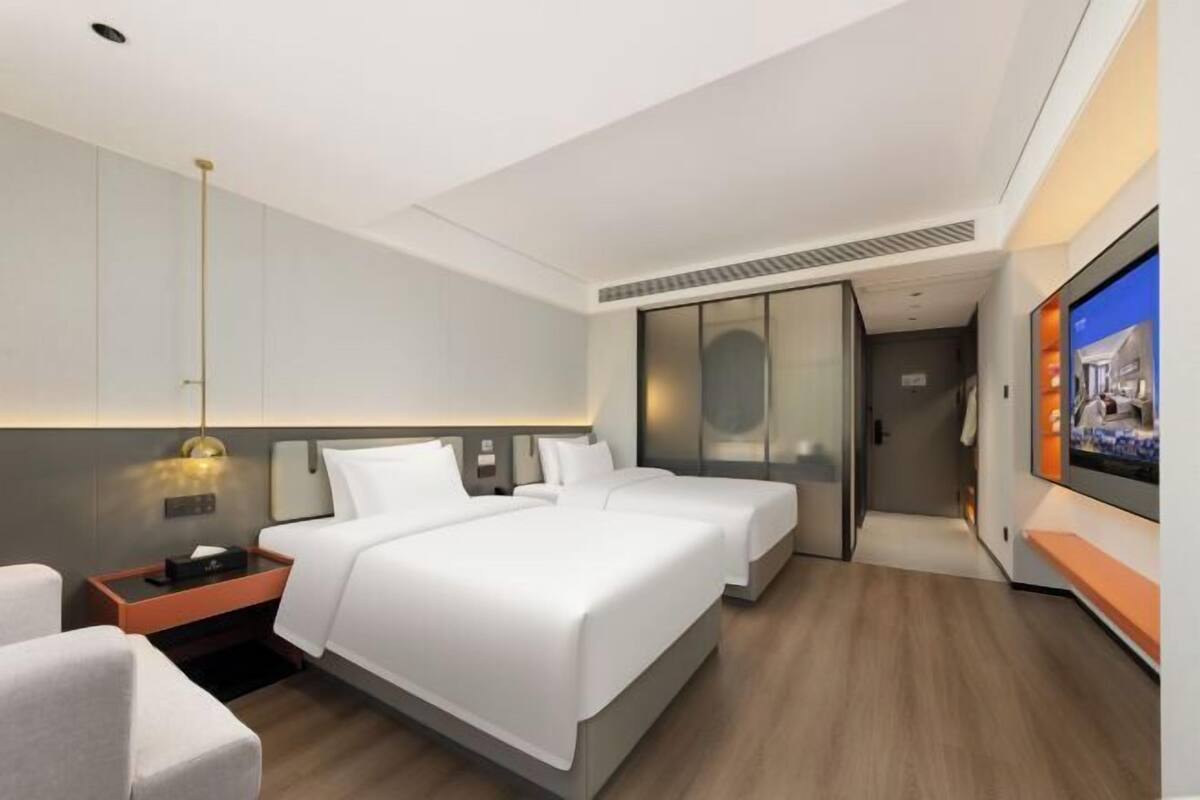 A hotel room with two beds, a TV, a desk, and a wardrobe.