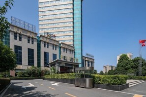 A modern hotel with a prominent glass facade, a well-maintained entrance area with directional arrows, and a flagpole with a flag. - Hongyuan Hotel (Gucheng)