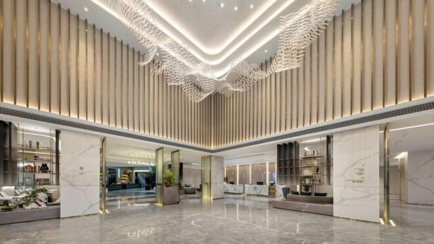 Un hall d’entrée spacieux avec un plafond haut, un éclairage moderne et un espace salon central.
