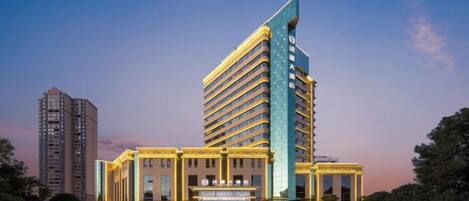 Un hotel de varios pisos con una estructura vertical destacada, una entrada central y un área exterior bien cuidada.