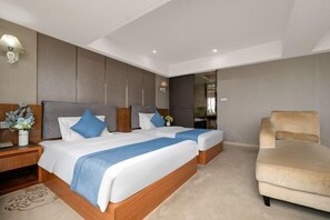 Habitación de hotel con dos camas, un sofá, una mesita de noche y un espejo.