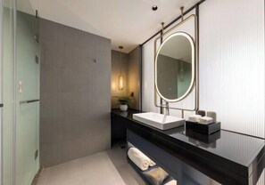 A modern bathroom with a glass shower enclosure, a black vanity with a white sink, and a large mirror. - Hongyuan Hotel (Gucheng)