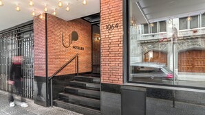 Entrada de un hotel con fachada de ladrillo, una escalera y una puerta de cristal que da al interior.
