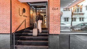 Entrada de hotel con fachada de ladrillo, número de domicilio visible y una escalera que da al interior.