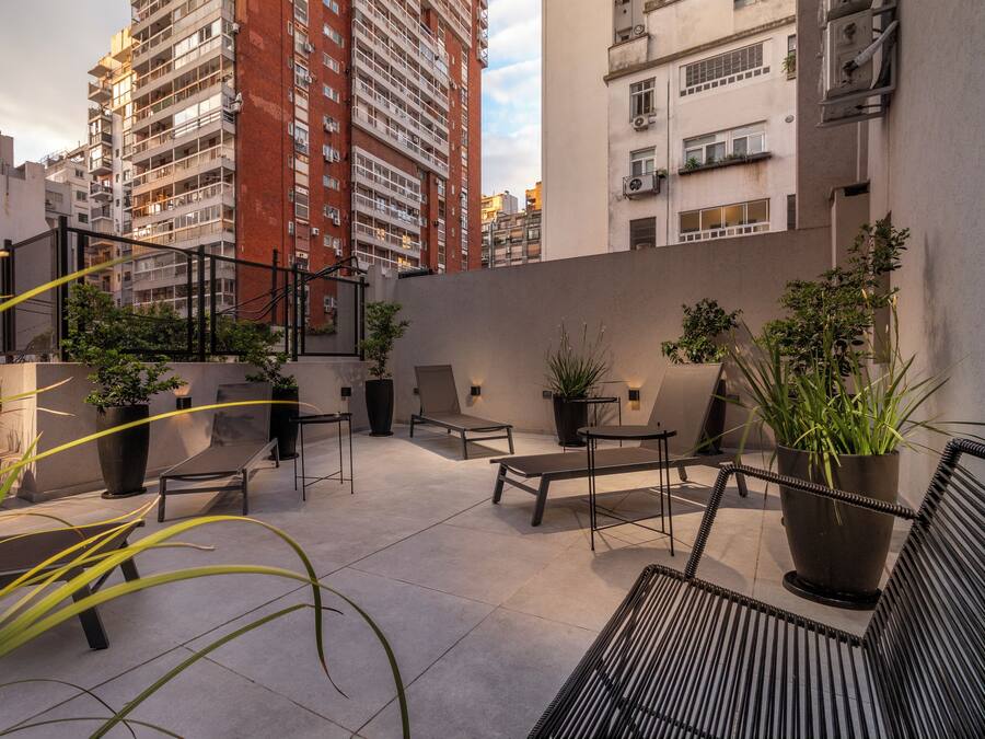 An outdoor patio area with seating, potted plants, and a view of surrounding buildings.