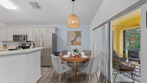 A modern kitchen with white cabinets, a central island, and a dining area with a round table and chairs. - 5 Bedroom Spacious Home with Private Pool and Resort Pool in Terra Verde Resort (Kissimmee)