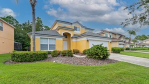 A single-story house with a yellow facade, a front entrance, and a well-maintained lawn. - 5 Bedroom Spacious Home with Private Pool and Resort Pool in Terra Verde Resort (Kissimmee)