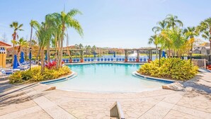 A swimming pool with blue lounge chairs and palm trees. - 5 Bedroom Spacious Home with Private Pool and Resort Pool in Terra Verde Resort (Kissimmee)