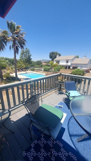 A deck with a pool, lounge chairs, and a table.