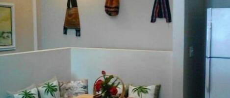 Ett kompakt kök med ett matbord, ett kylskåp och en soffa med dekorativa kuddar.