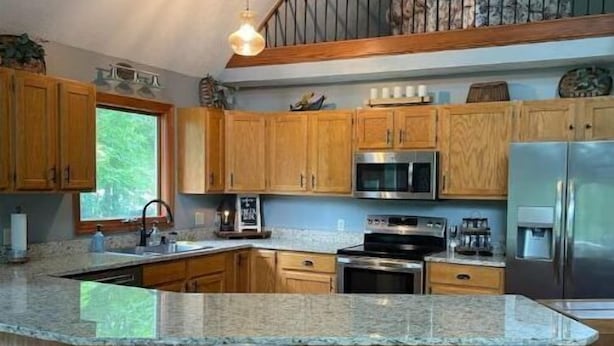 A modern kitchen with wooden cabinets, a granite countertop, stainless steel appliances, and a bar stool seating area. - Creekside a piece of heaven (Gallipolis)