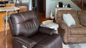 A spacious living area with a high ceiling, a wooden staircase, and a kitchen with modern appliances. - Creekside a piece of heaven (Gallipolis)