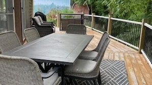 An outdoor patio with a table and chairs, a covered area, and a view of a building and trees. - Creekside a piece of heaven (Gallipolis)
