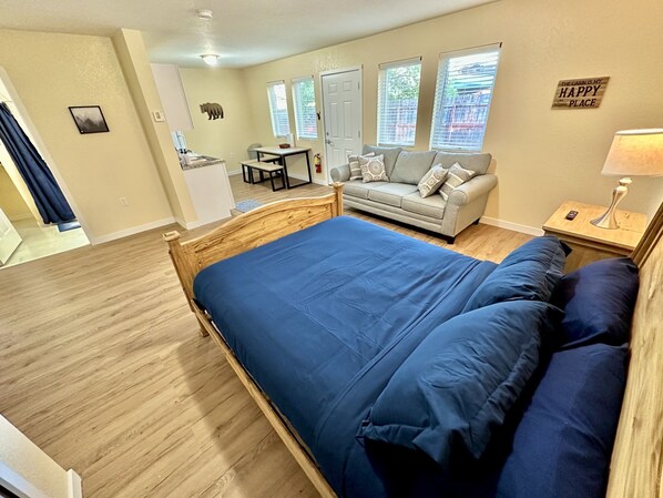 A bedroom with a large bed, a sofa, a small table, and a lamp.