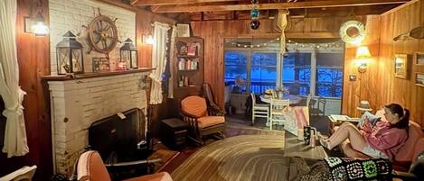Un interior acogedor y rústico, con vigas de madera, una chimenea y vistas al exterior.
