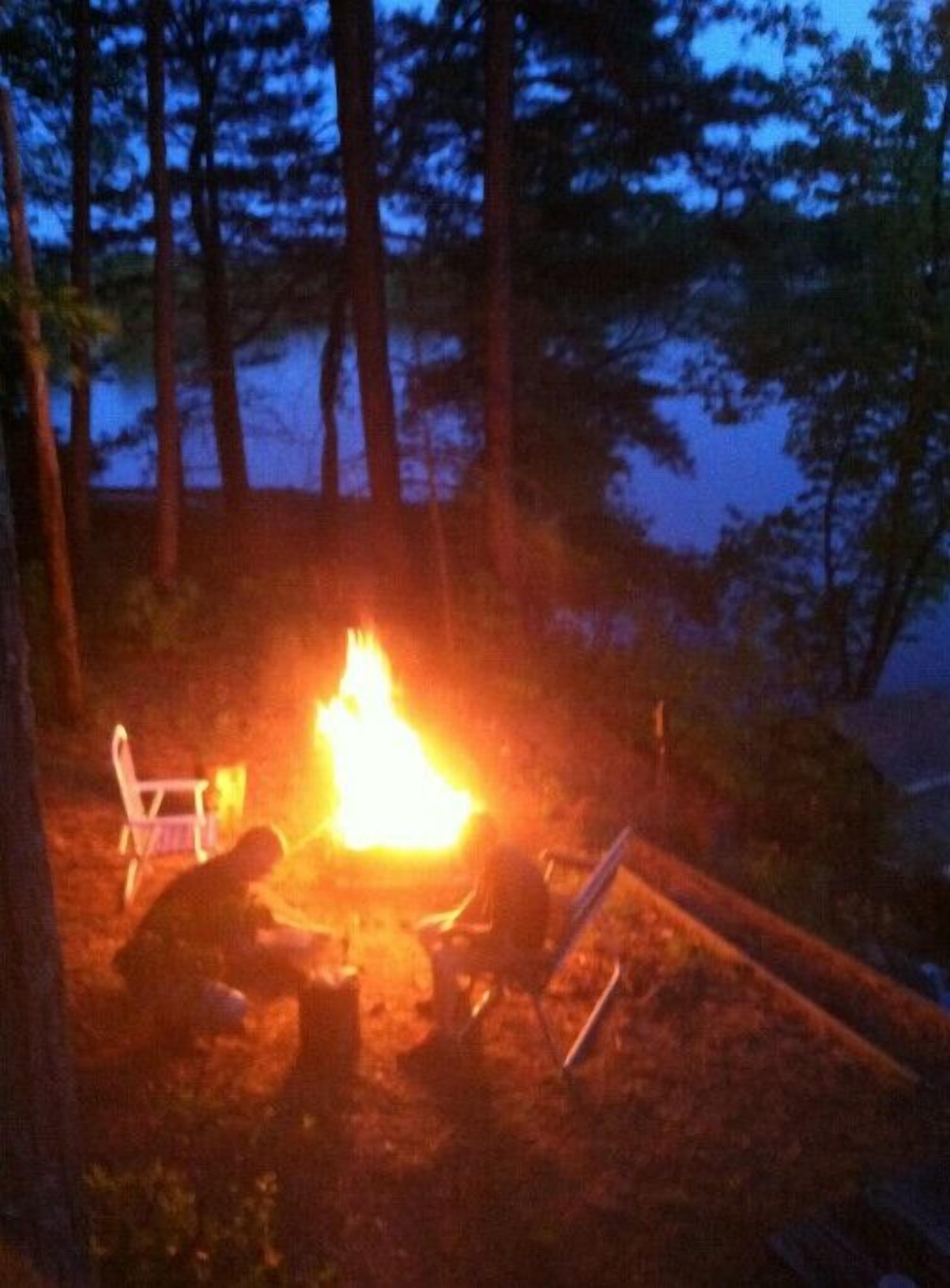 Un fuoco da campo con una sedia e un tavolo nelle vicinanze, in un ambiente boschivo.