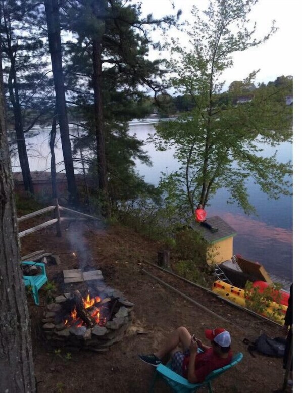 A lakeside setting with a fire pit, outdoor seating, and a view of the lake. - LAKE FRONT ISLAND HIDE-AWAY WITH BOAT DOCK (Southwick)