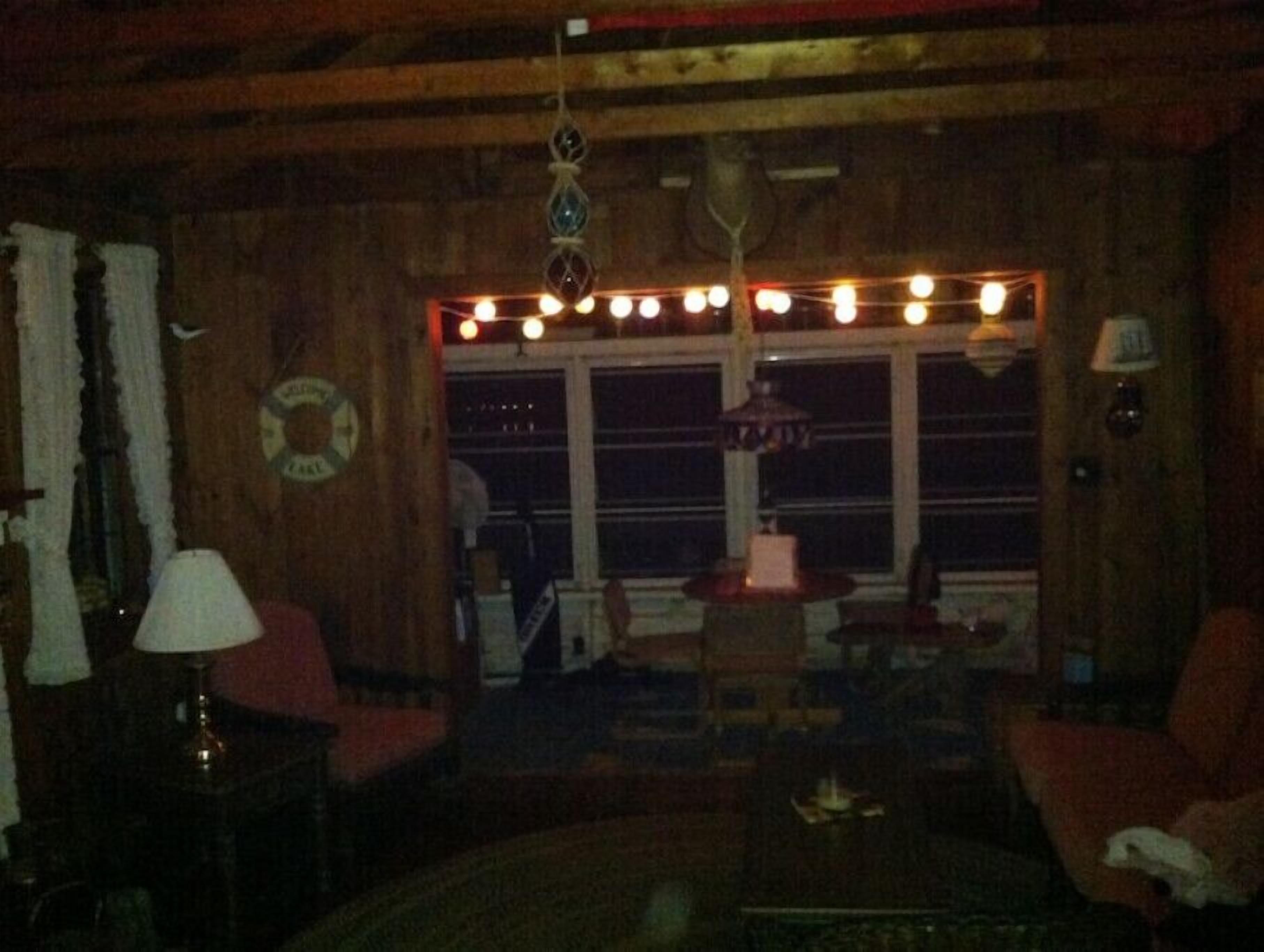 Ein schwach beleuchteter Holzraum mit Kamin, Tisch und Stuhl.