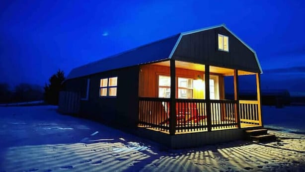 A single-story cabin with a porch, large windows, and a visible door.