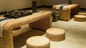 A room with a woven bench, a small table with a tray, and two round stools. - Huifeng Hotel (Longkou)
