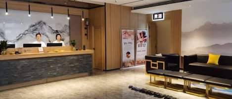 A reception area with a reception desk, a seating area with sofas, and a wall with a mountain mural.