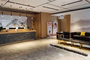 A reception area with a reception desk, a seating area with sofas, and a wall with a mountain mural.