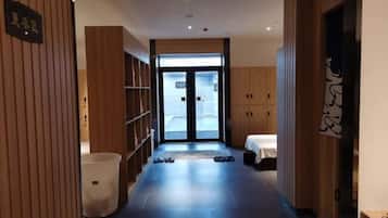 Pasillo de hotel con paneles de madera, un mostrador de recepción y una cama al fondo.
